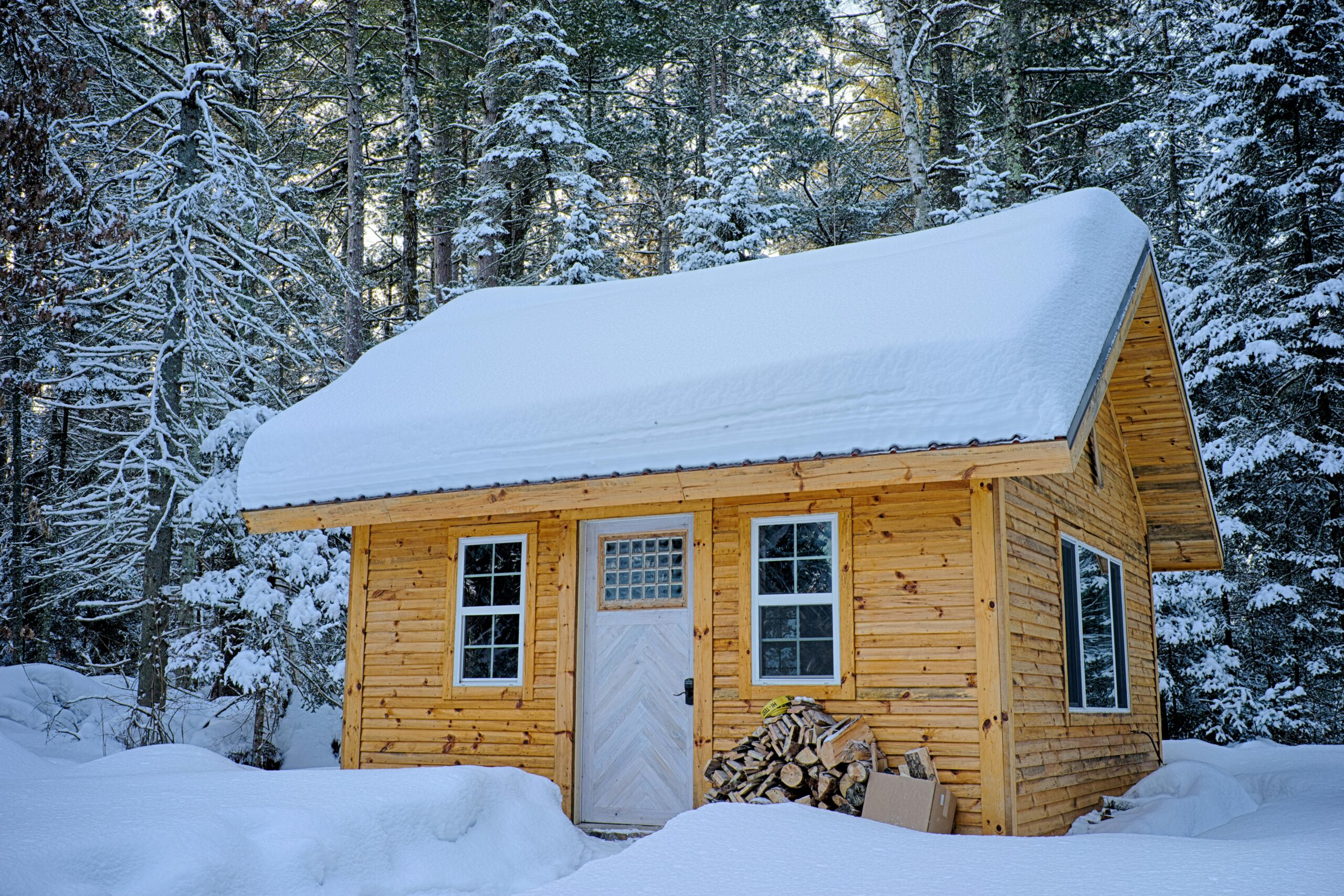 A scenic wooden cabin surrounded by snow-covered trees in a peaceful winter landscape.